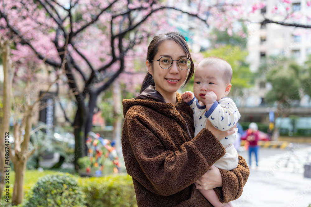 Mother taking picture with baby under Sakura blossoms