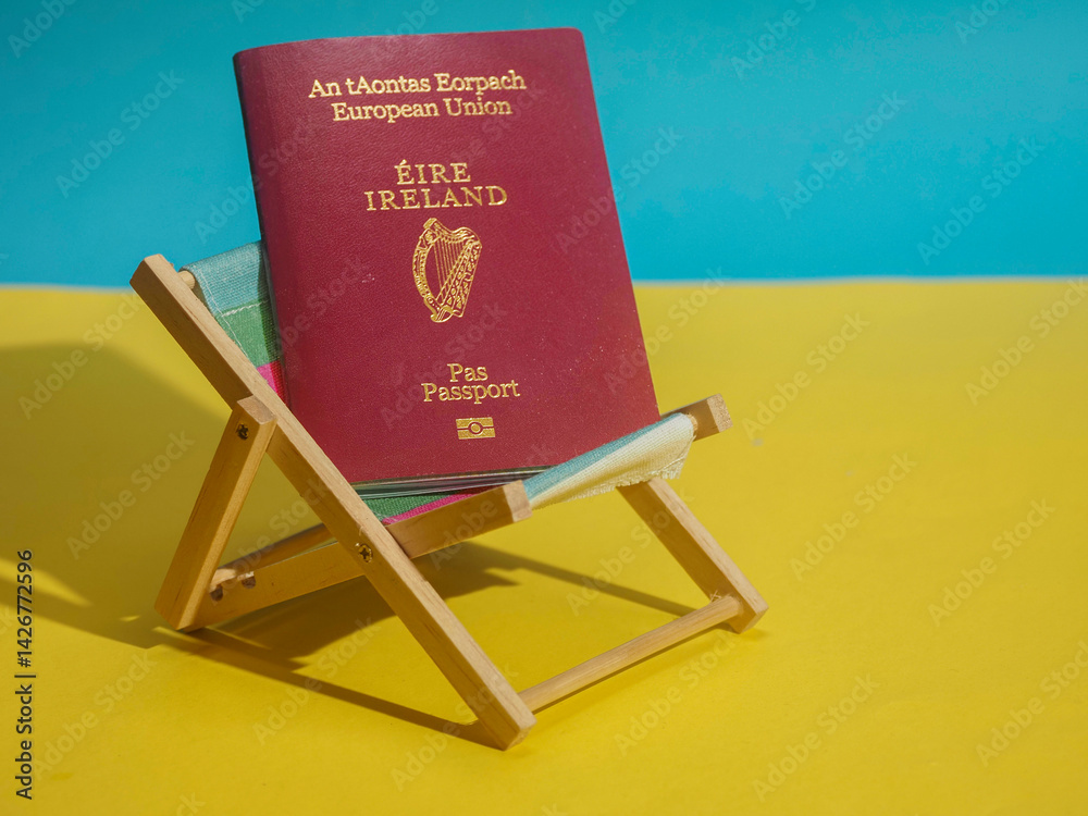 Passport of Ireland on a sun lounger and on yellow sand and blue water background. Irish citizens travel to exotic places concept. Copy space, Cost and price of sunny holiday theme.