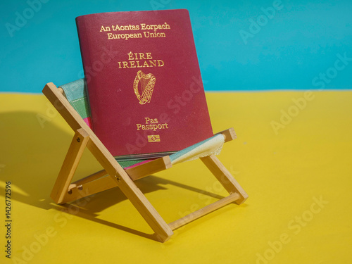 Obraz na płótnie Passport of Ireland on a sun lounger and on yellow sand and blue water background. Irish citizens travel to exotic places concept. Copy space, Cost and price of sunny holiday theme. w salonie