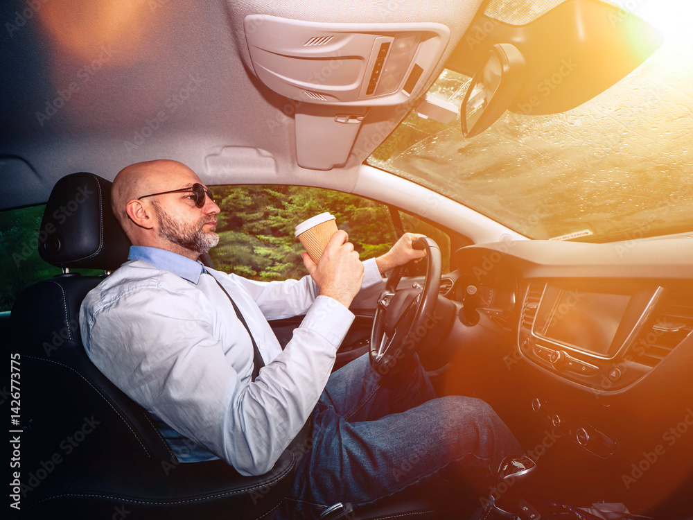 A man in a white shirt and sunglasses is driving a car. He is wearing a tie and sunglasses, and the car is parked in a nature area with green trees. Unwind after hard working day concept.