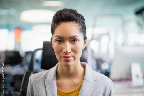 Free Download Young adult Chinese businesswoman sitting in chair in office among monitors and overhead lights - GFXLoad