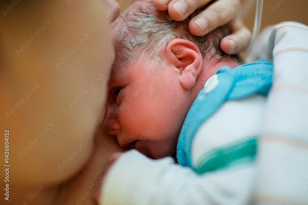 Newborn baby wrapped in blankets after birth. Mother looking for the first time on new born daughter. Newborn child seconds and minutes after birth. Happy mum crying