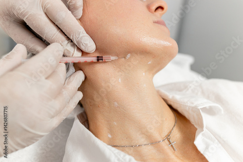 Hands of a beautician during biorevitalization or botulinum therapy of the skin of a woman's neck - close-up 