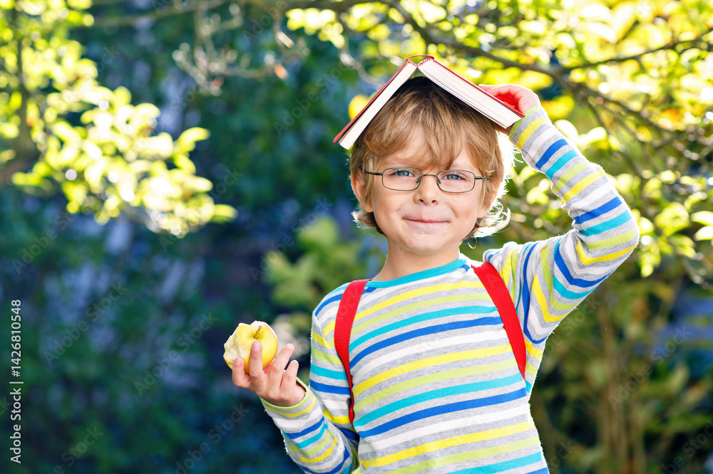 Happy little preschool kid boy with glasses, books, apple and backpack on his first day to school or nursery. Funny healthy child outdoors on warm sunny day, Back to school concept. Laughing boy.