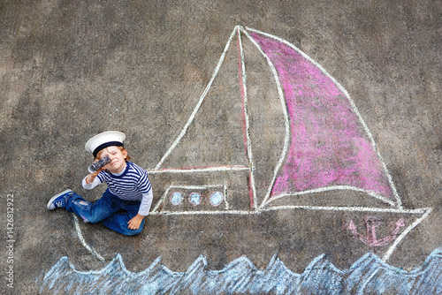 Obraz na płótnie Little kid boy as pirate on ship or sailingboat picture painting with colorful chalks on asphalt. Creative leisure for children outdoors in summer. Child with captain hat and binoculars. w salonie