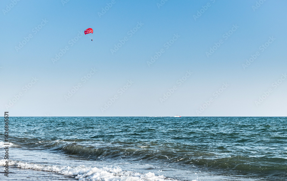 A red parachute flies over the sea A red parachute flies over the sea