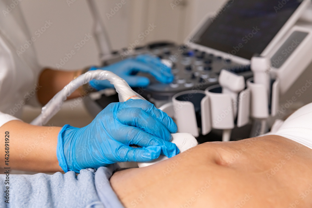 In the hospital, close-up shot of the doctor does ultrasound sonogram procedure to a pregnant woman. Obstetrician moving transducer on the belly of the future mother. High quality photo