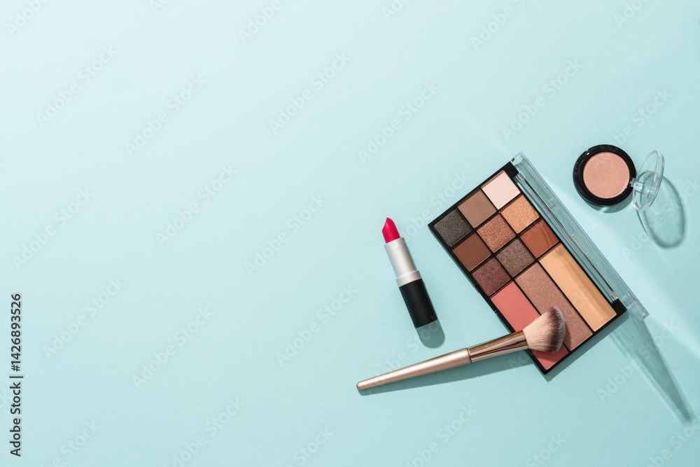 Make up products on blue background. Cosmetic palette, brushes and lipstick. Flat lay with copy space.