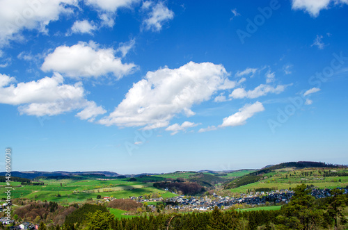 White irregular clouds against a blue beautiful sky in summer. Villages of Germany with mountains and forest.