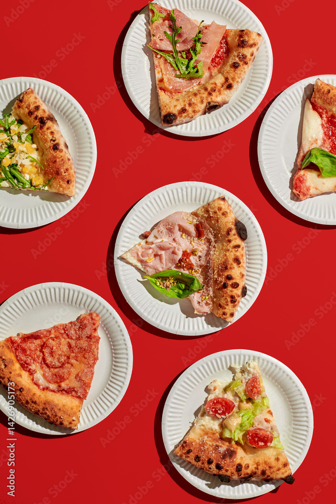 Variety of gourmet pizza slices displayed on disposable plates, vibrant red background