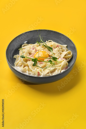 Obraz na płótnie Creamy carbonara pasta with egg yolk and pea shoots on vibrant yellow background w salonie