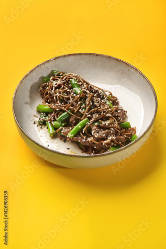 Obraz na płótnie Soba noodles with beef and green onions on vibrant yellow background w salonie