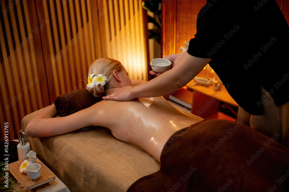 Caucasian woman customer enjoying relaxing anti-stress spa massage and pampering with beauty skin recreation leisure in warm candle lighting ambient salon spa at luxury resort or hotel. Quiescent