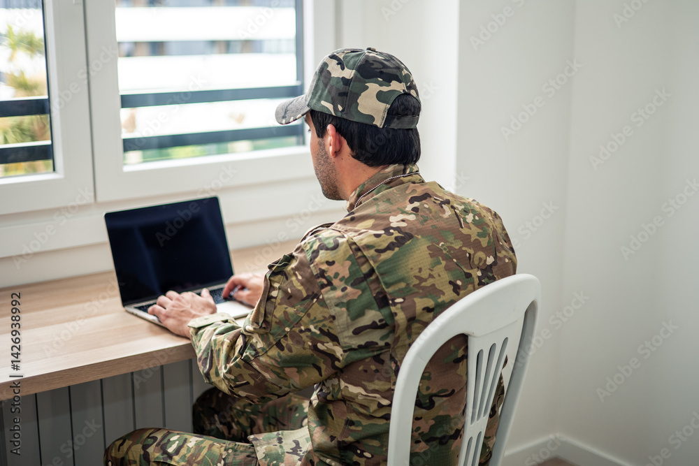 Fototapeta premium Soldier working from home using laptop computer