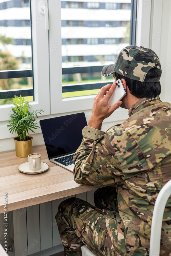 Obraz premium vertical Soldier talking on the phone while working from home