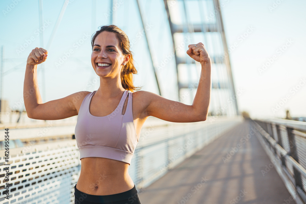 Confident Athletic Woman Flexing on a Modern Bridge at Sunset