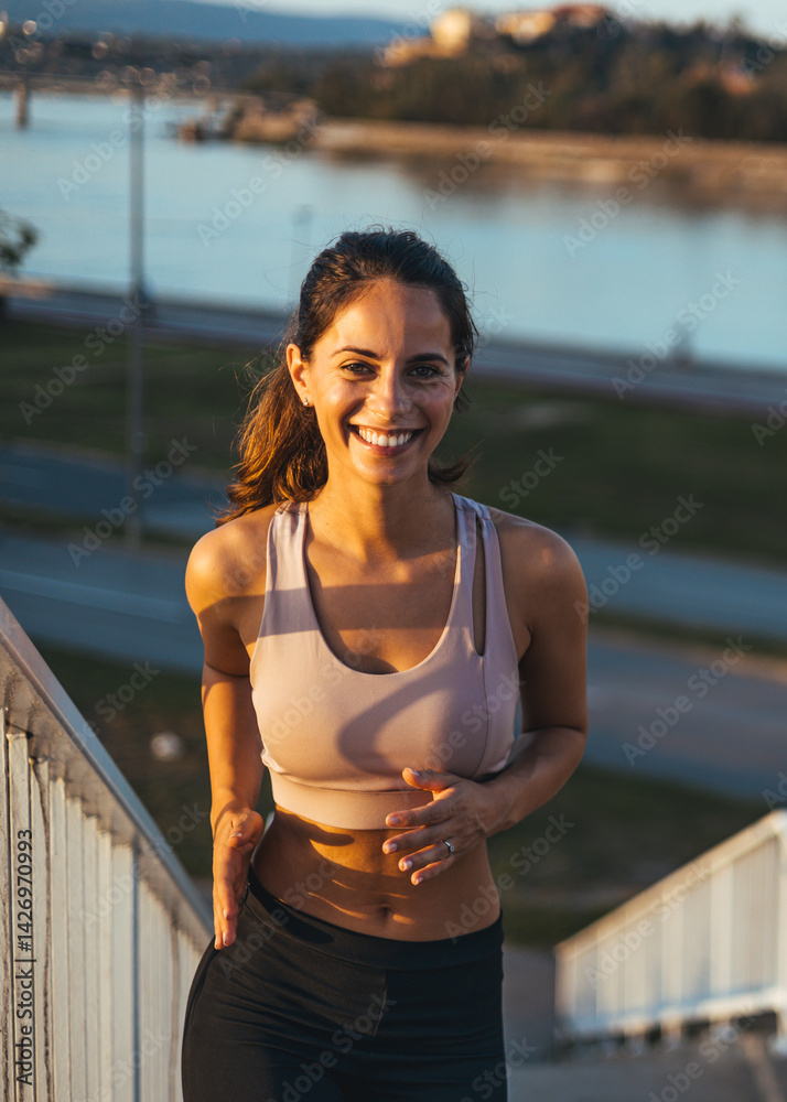 Smiling Woman Jogging Outdoors by the Water in the Morning Sun