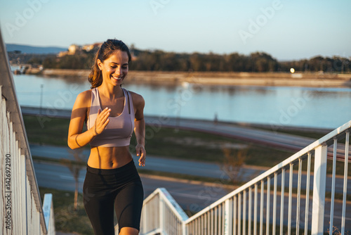 Obraz na płótnie Young Woman Running Up Stairs Outdoors With A River Background w salonie