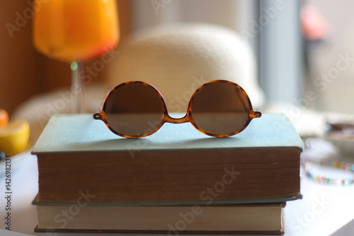 Glass of cocktail, straw hat, sunglasses, books, fresh fruit, chocolate and accessories. Summer essentials on the table. Selective focus.