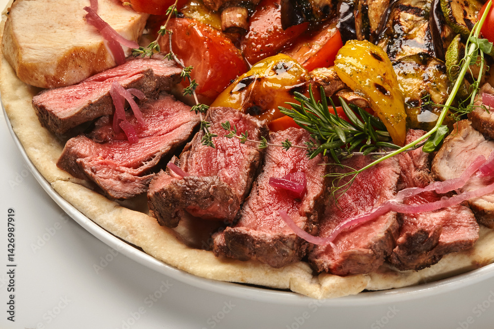 Sliced grilled beef tenderloin with grilled vegetables and pita bread