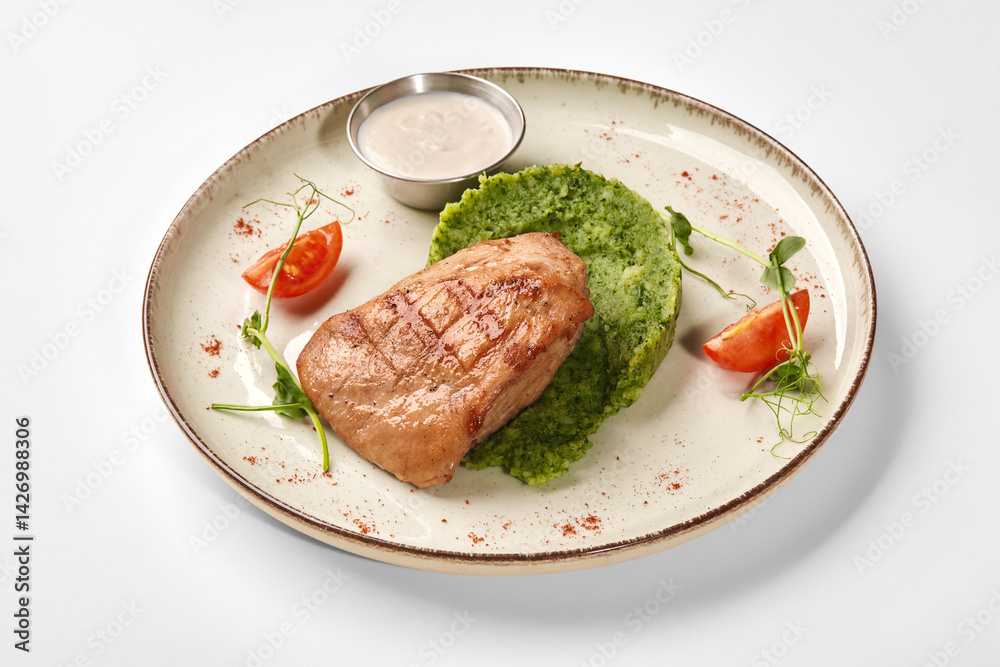 Grilled chicken breast with green puree and cherry tomatoes on elegant plate