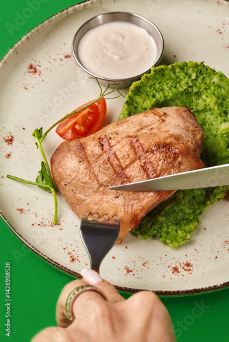 Obraz na płótnie Woman eating grilled chicken breast with green puree and white sauce w salonie