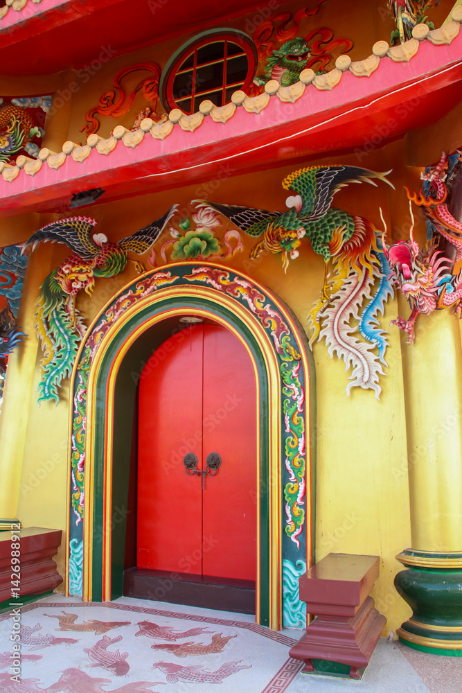 Obraz premium Red door on a yellow building decorated with dragon designs