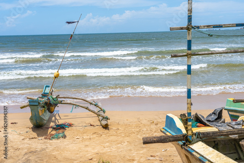 Obraz na płótnie Colourful traditional style outrigger canoe with fishing nets and gear pulled up on beach. w salonie