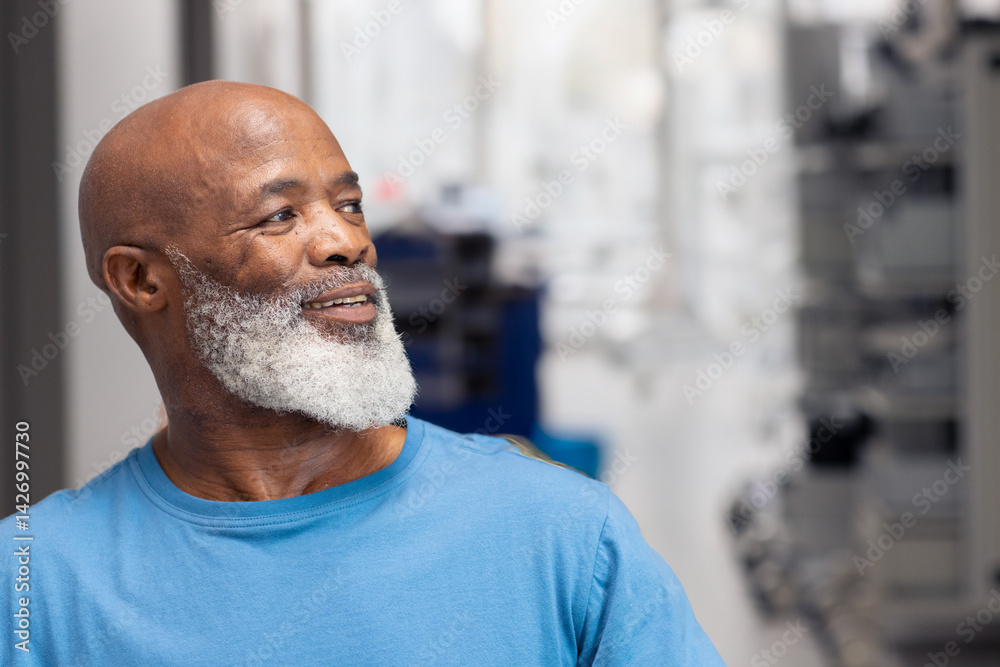 Senior African American man smiling gently and looking at lab equipment in indoor lab setting