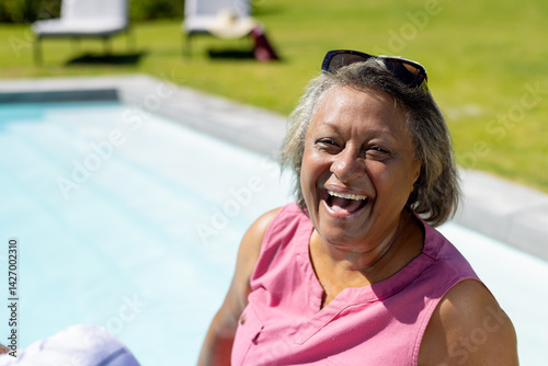 Obraz na płótnie Relaxed senior woman enjoying sun on pool edge in backyard with sunglasses, copy space w salonie