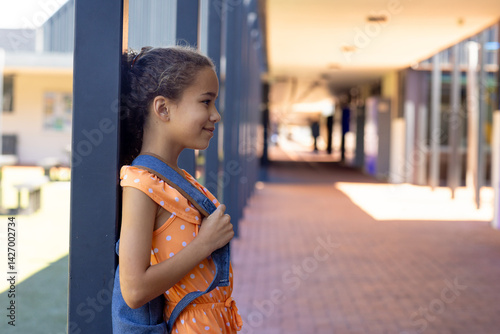Obraz na płótnie Girl child standing in profile at covered school walkway, holding denim backpack strap, copy space w salonie