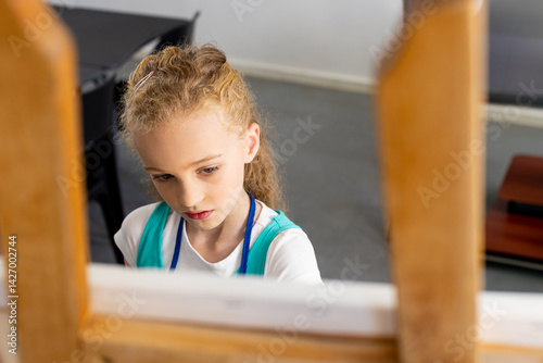 Obraz na płótnie Female child painting on canvas behind wooden art easel in art studio, featuring black table w salonie