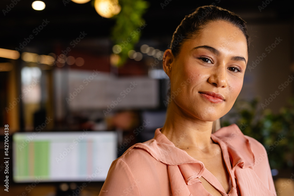 Business woman standing in open?plan office with data monitor, pendant lights and plant, copy space