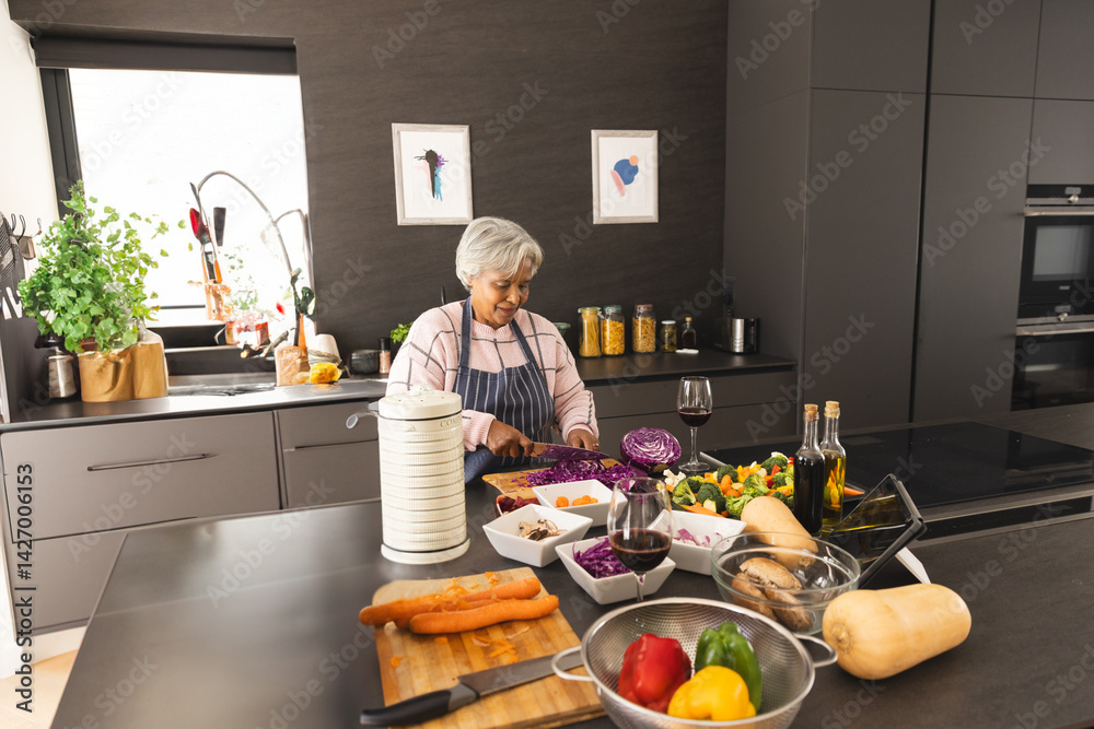 Senior woman chopping red cabbage into white bowl at home kitchen island with wooden cutting board