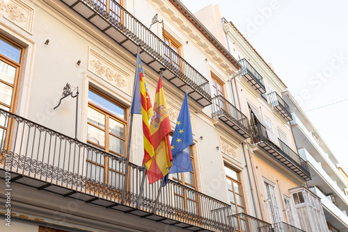 Obraz na płótnie Two Spanish flags in the wind. Spanish flags and EU flag on the wall of a house. Flags in the facade of old building. w salonie