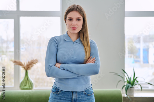 Obraz na płótnie Portrait of confident young woman posing with crossed arms in home interior w salonie