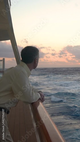 Vertical video of single senior man watching sunset from deck of cruise ship with pan to the sun