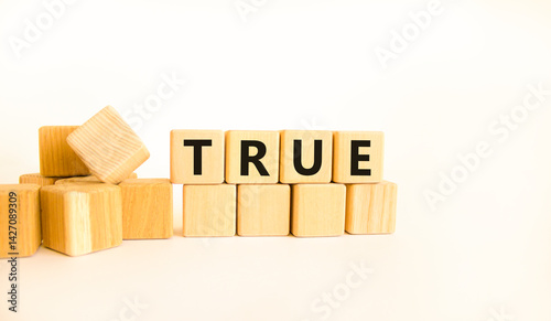 True symbol. Concept word True on beautiful wooden blocks. Beautiful white table white background. Business, lifestyle, support and true concept. Copy space.