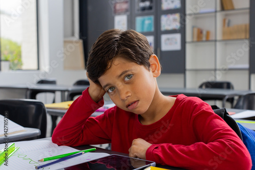 Obraz na płótnie Boy resting head on hand at student desk in classroom, with open notebook pencil ruler tablet w salonie