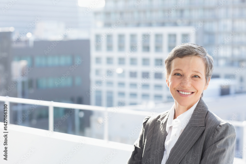 Woman leaning against white metal railing on rooftop deck overlooking office buildings, copy space