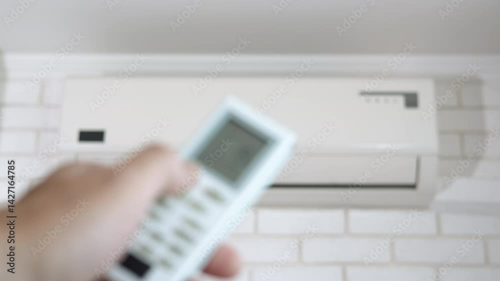 Man arm with remote power by air conditioner. A view of man arm with remote power change the temperature in the room during summer time. Man arm with remote power by air conditioner. A view of man arm with remote power change the temperature in the room during summer time.