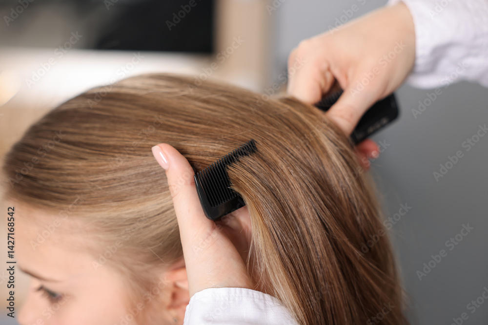 Naklejka premium Hairdresser doing girl's hairstyle in salon, closeup