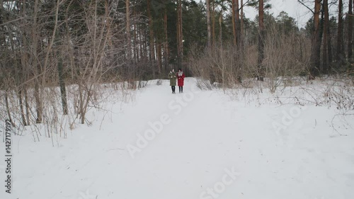 Friends explore a snowy landscape during winter in a forested area, enjoying nature and company