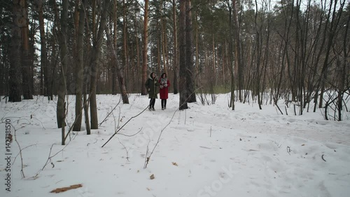 Friends explore a snowy landscape during winter in a forested area, enjoying nature and company