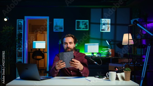 Obraz na płótnie Tech expert presenting tablet in entry level low budget price range to interested viewers, filming in studio. Viral content creator reviewing digital device in front of internet audience, camera B w salonie