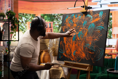 Obraz na płótnie Artist listening to music and creating an abstract painting with his fingers, showing his skills and contemporary ideas in art studio. Creative process finger painting for vibrant artwork. w salonie