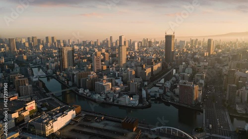 osaka city central minami ward aerial view drone at sunrise,flying over kizu river,high-rise office buildings in the background,metropolis cityscape