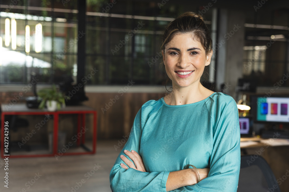 © Wavebreak Media - Female office worker standing and smiling in open-plan office with computer monitors, copy space