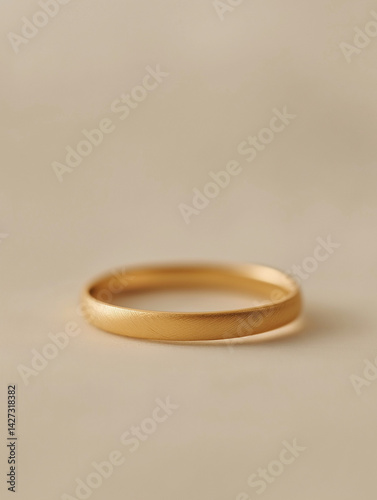 Single gold ring isolated on soft beige surface, minimal and modern style