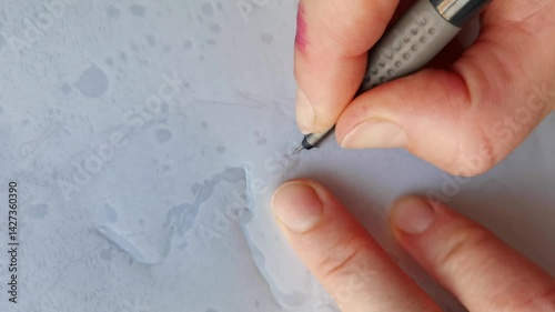 Artistic hand of a caucasian adult engraving on paper with intricate lines and precise movements.